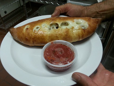 Our Cheese Mozzarella Calzone dish with a side Of Marinara Sauce